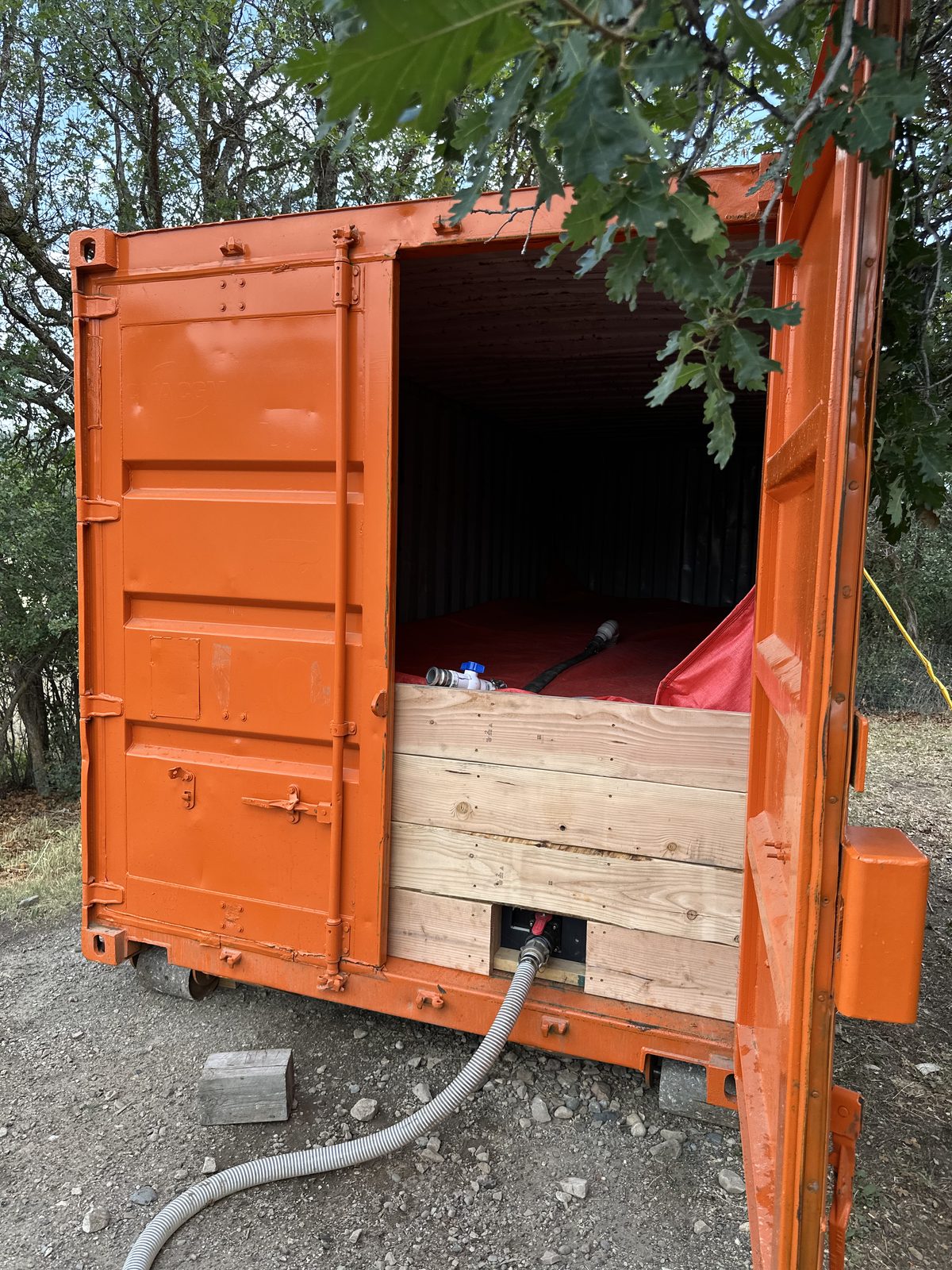 HOT BOX deployed on-site — container open showing bladder, retention dam, and discharge hose connected