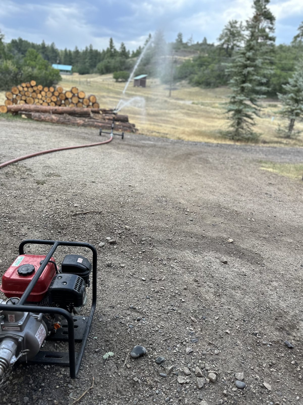 HOT BOX™ full deployment — pump, hose, and wheeled sprinkler protecting property